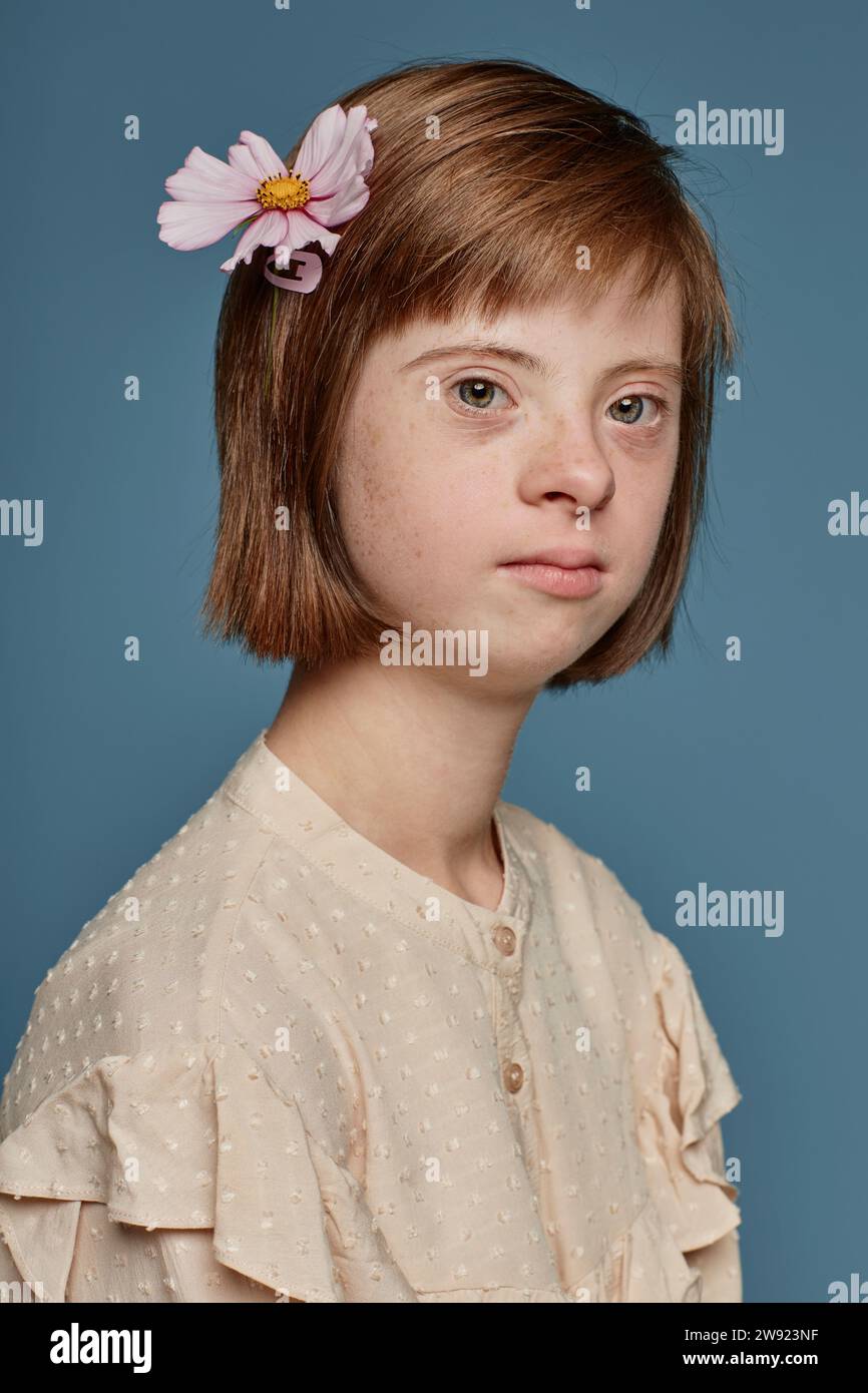Adolescente avec le syndrome de Down avec fleur dans les cheveux par fond bleu Banque D'Images