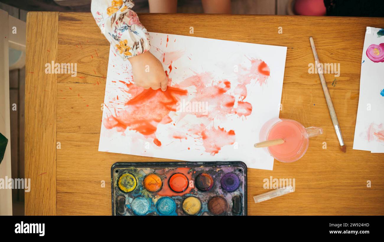 Main de fille peinture sur papier avec aquarelle à la maison Banque D'Images