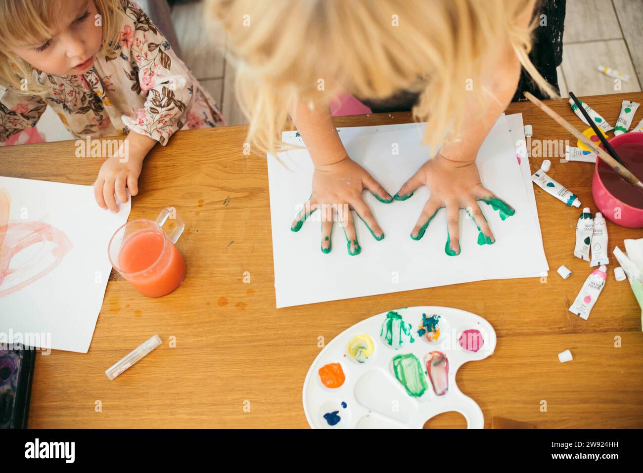 Fille faisant l'empreinte de main avec des aquarelles sur papier à la maison Banque D'Images