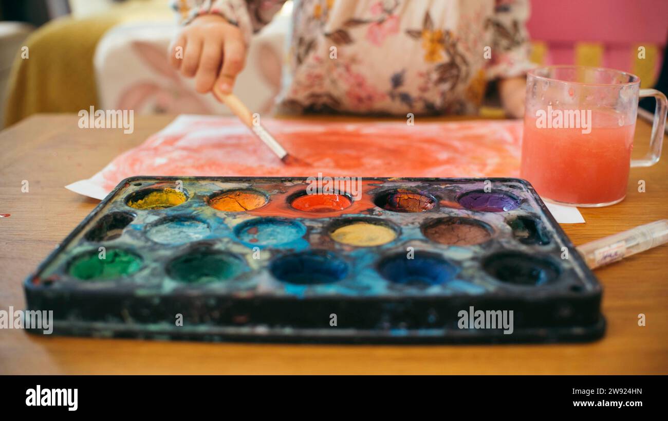 Fille utilisant des aquarelles pour peindre sur papier à la maison Banque D'Images