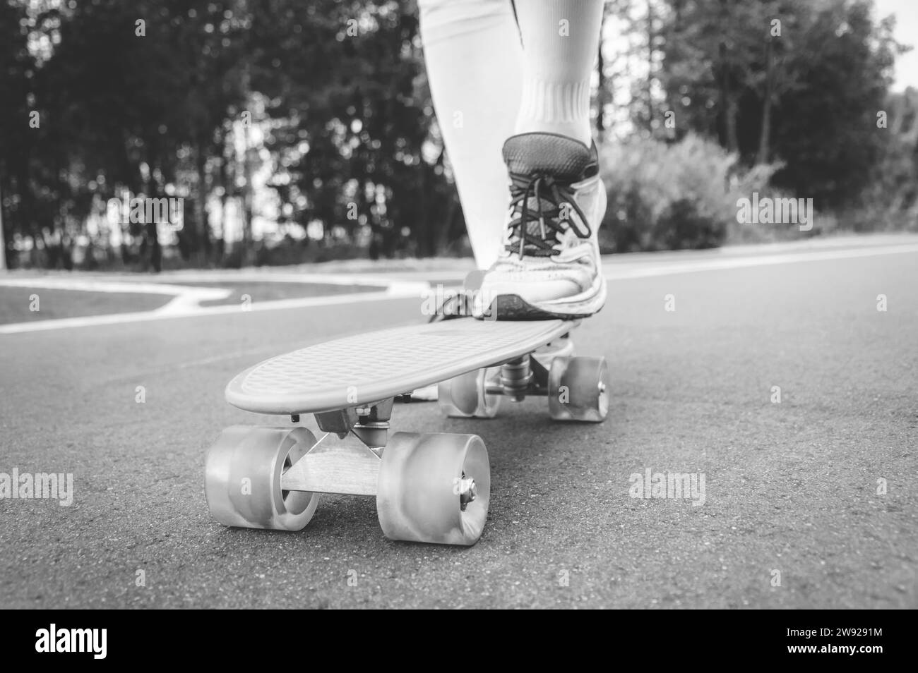 Images d'une jambe debout sur un skateboard. Soirée ensoleillée dans le parc. Concept de skateboard. Supports mixtes Banque D'Images