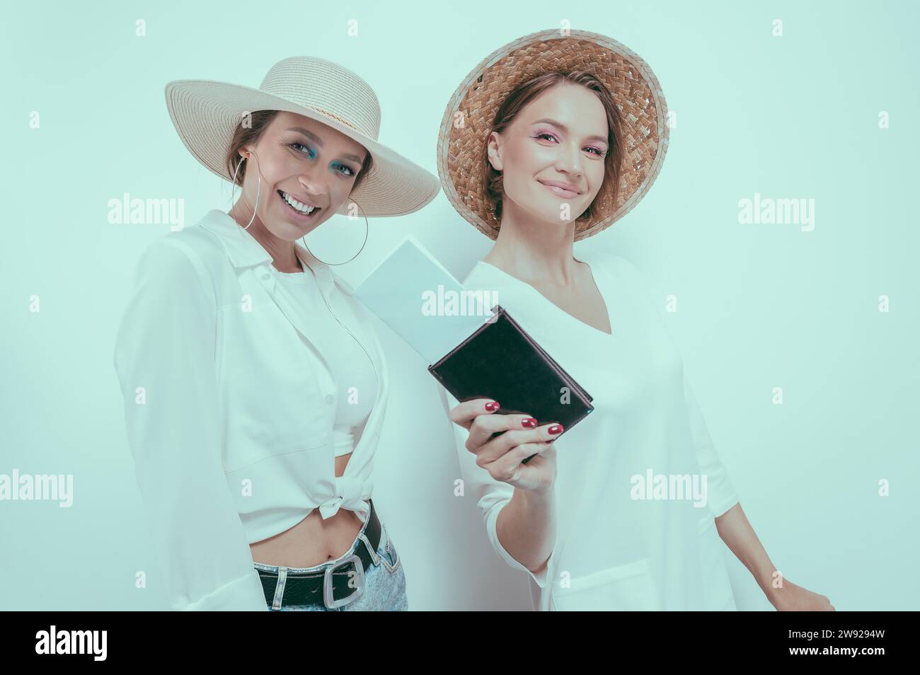 Portrait de deux femmes souriantes avec passeports et cartes d'embarquement dans leurs mains. Concept de voyage. Supports mixtes Banque D'Images