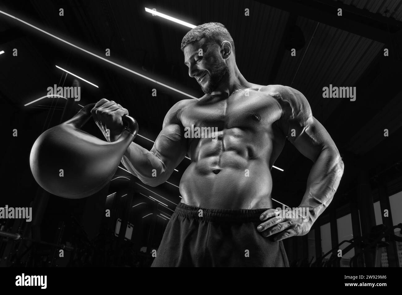 Homme musclé posant dans la salle de gym avec une kettlebell. Concept de fitness. Supports mixtes Banque D'Images