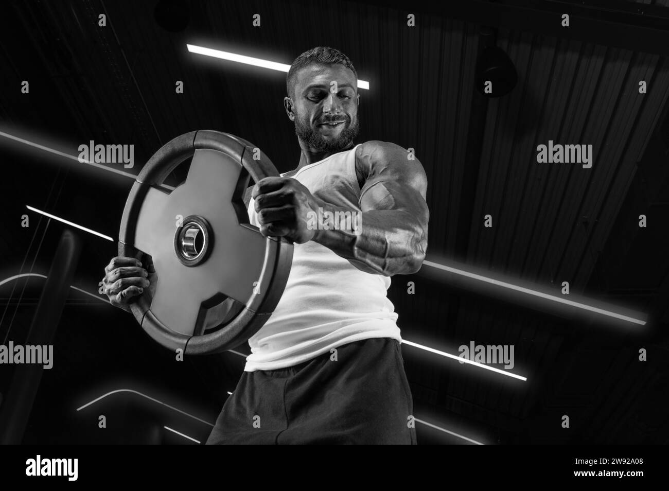 Image d'un gars musclé en maillot blanc avec un équipement sportif. Gym. Concept de fitness Banque D'Images