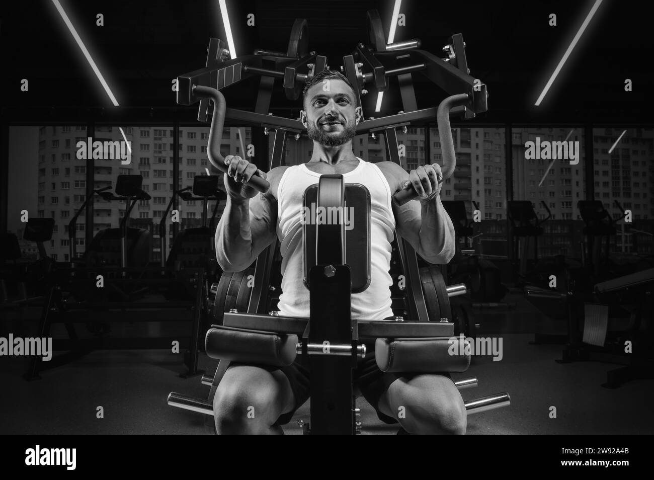 Image d'un gars musclé dans un débardeur blanc sur une machine d'exercice. Gym. Concept de fitness Banque D'Images