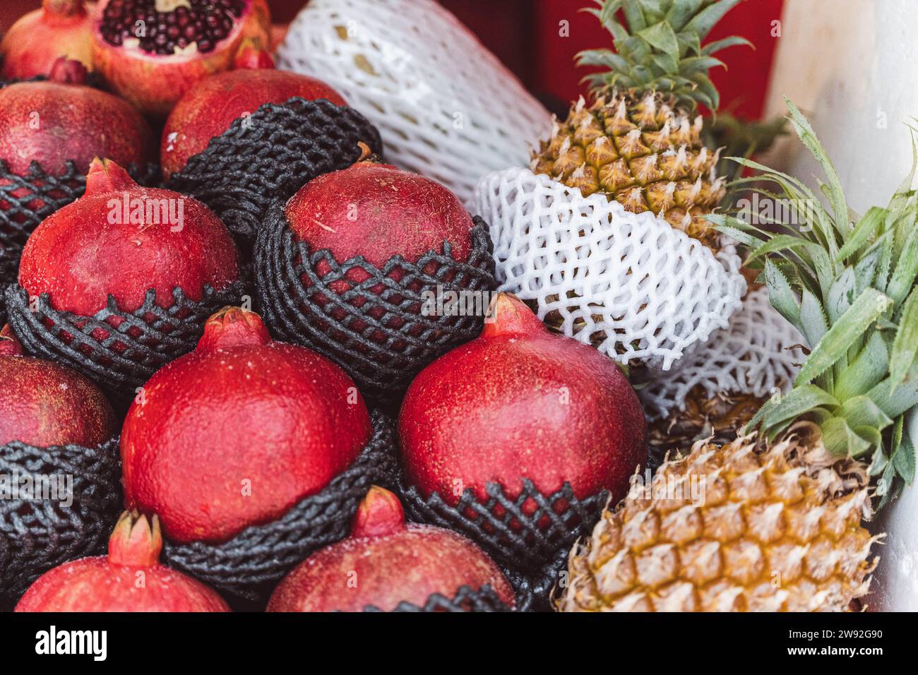 Une exposition de grenades et d'ananas frais et mûrs sur une étagère soignée, avec une variété de couleurs et de textures vibrantes, créant un oeil-catchi Banque D'Images