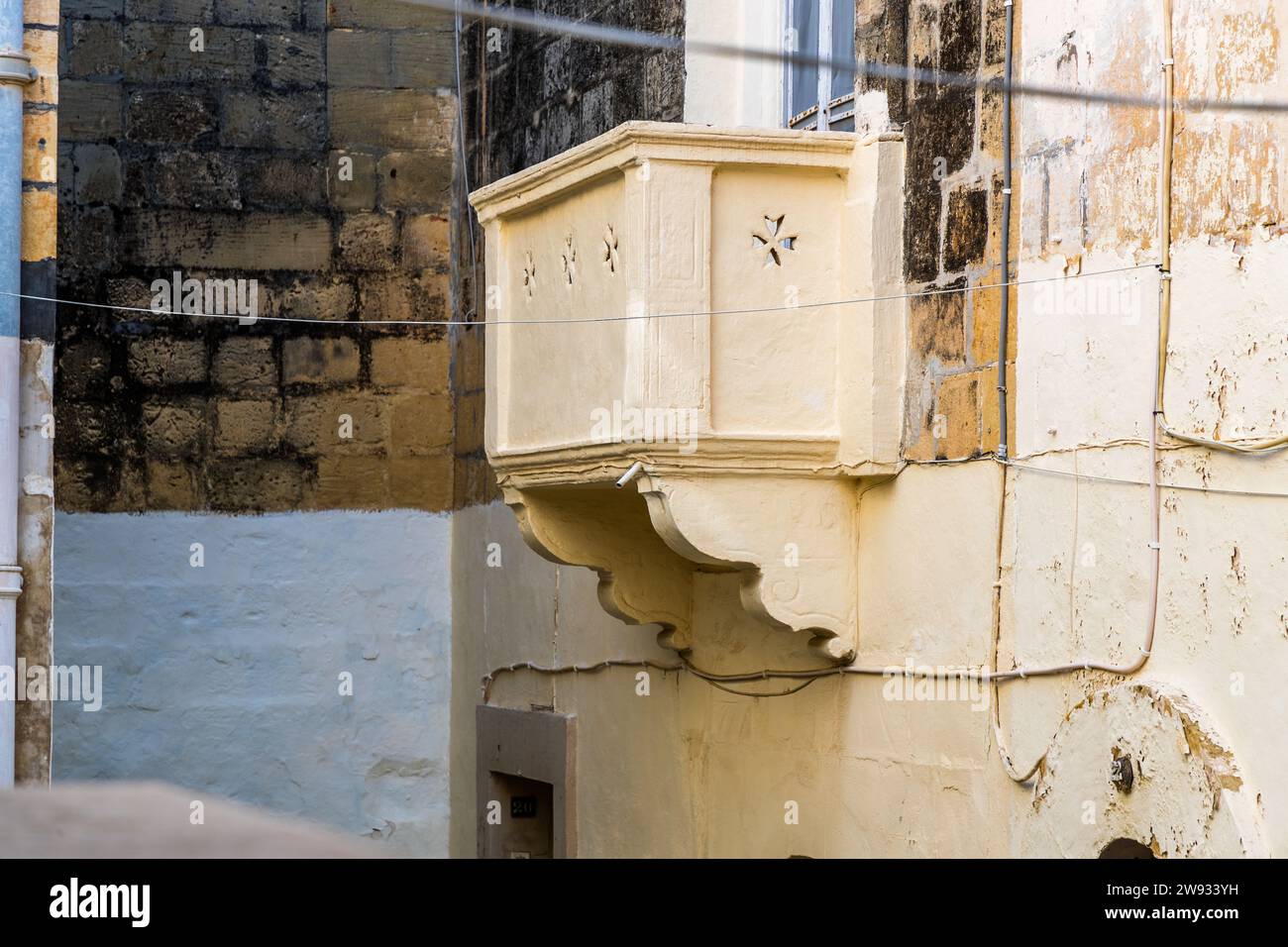 Victoria, la capitale insulaire de Gozo à Malte, est toujours appelée Rabat par ses habitants – officiellement rebaptisée en 1887 pour le Jubilé d'or de la reine Victoria. Un support de balcon simple en forme de boîte en calcaire pâle, sculpté de motifs d'étoiles, dépasse d'une façade de maison dans la vieille ville, sous une fenêtre non encore équipée d'une rambarde. Banque D'Images