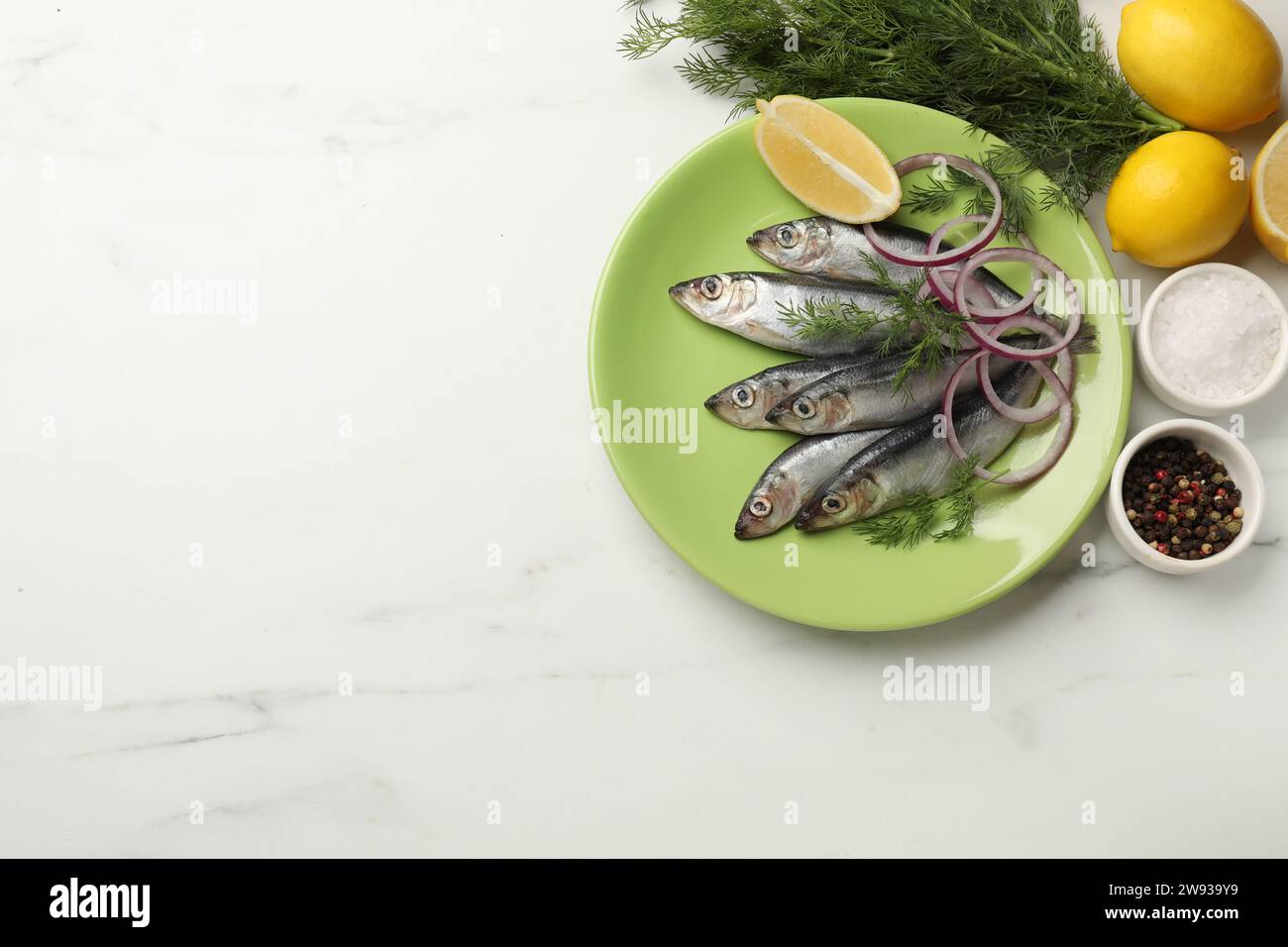 Sprats crus frais, citron coupé, oignon, aneth et épices sur table en marbre blanc, pose à plat. Espace pour le texte Banque D'Images