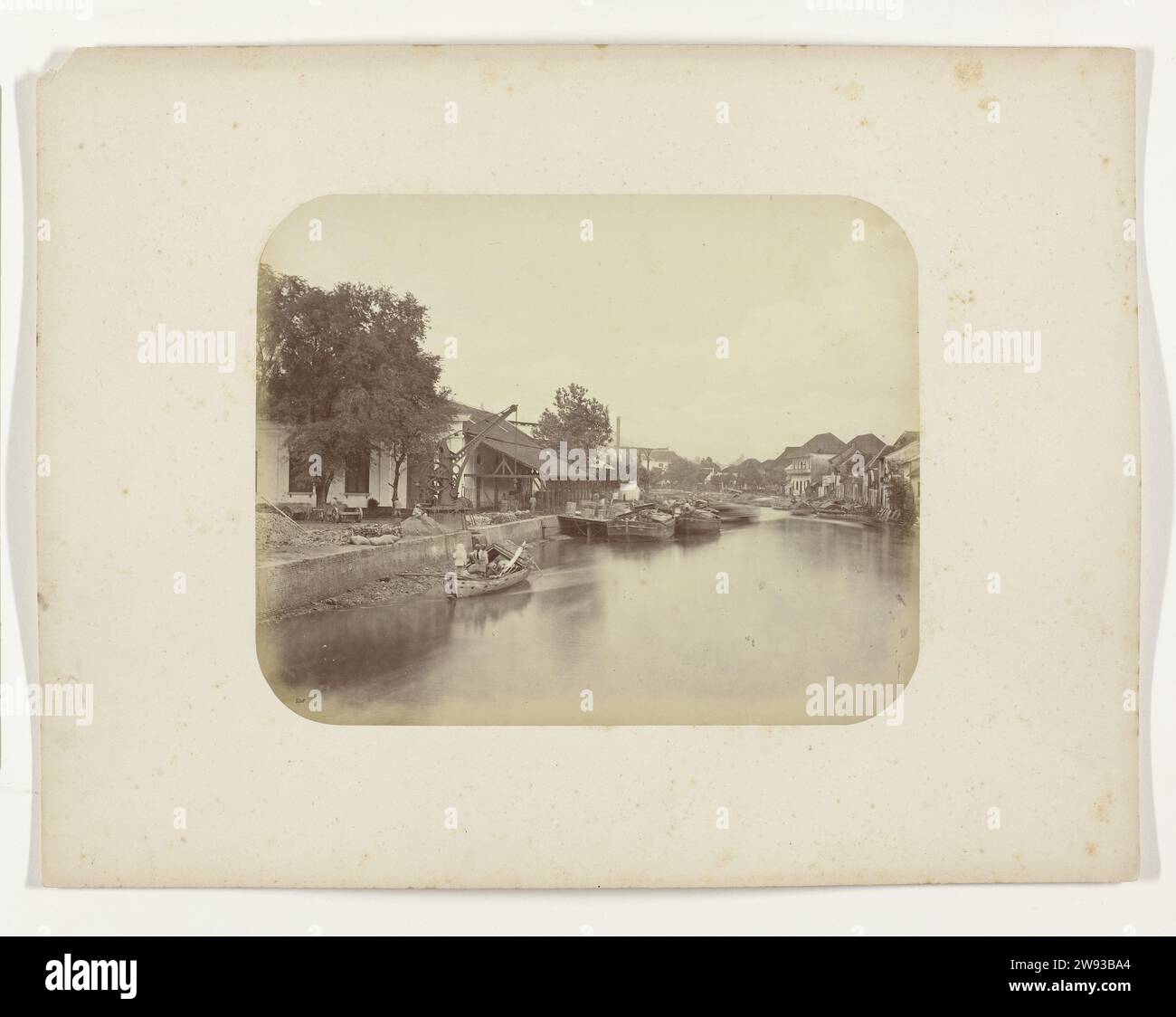 Vue du Mas Kali à Surabaya, Herman Salzwedel, 1876 - 1884 photographie vue du Mas Kali à Surabaya avec une poussette avec des personnages à gauche et un certain nombre de navires amarrés. A gauche une usine avec une grue et à droite une rangée de maisons sur la rivière. Partie de l'album photo du Surabayasche Vereeniging des fabricants de sucre offert à Frederik Beyerinck, résident de Surabaya. Surabaya support photographique albumen print Java. Surabaya Banque D'Images