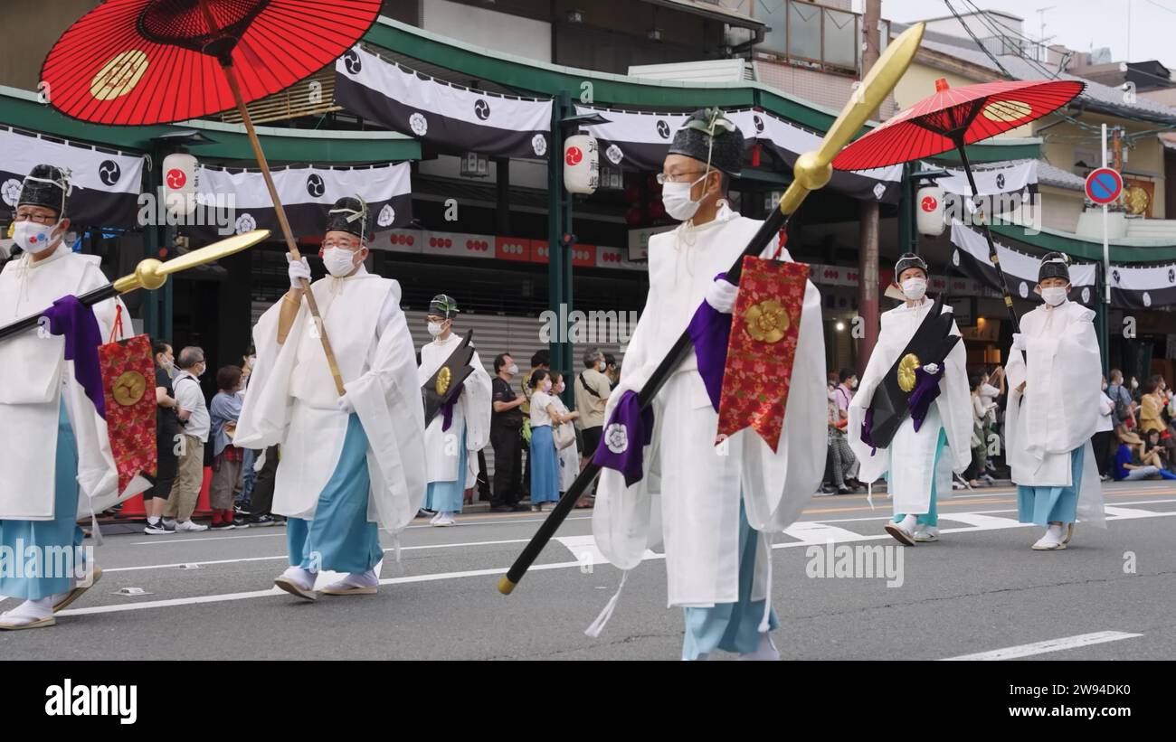 Aperçu du festival Aoi Matsuri à Kyoto au Japon présentant un homme orné d'une tenue traditionnelle tenant gracieusement un parapluie rouge vibrant Banque D'Images