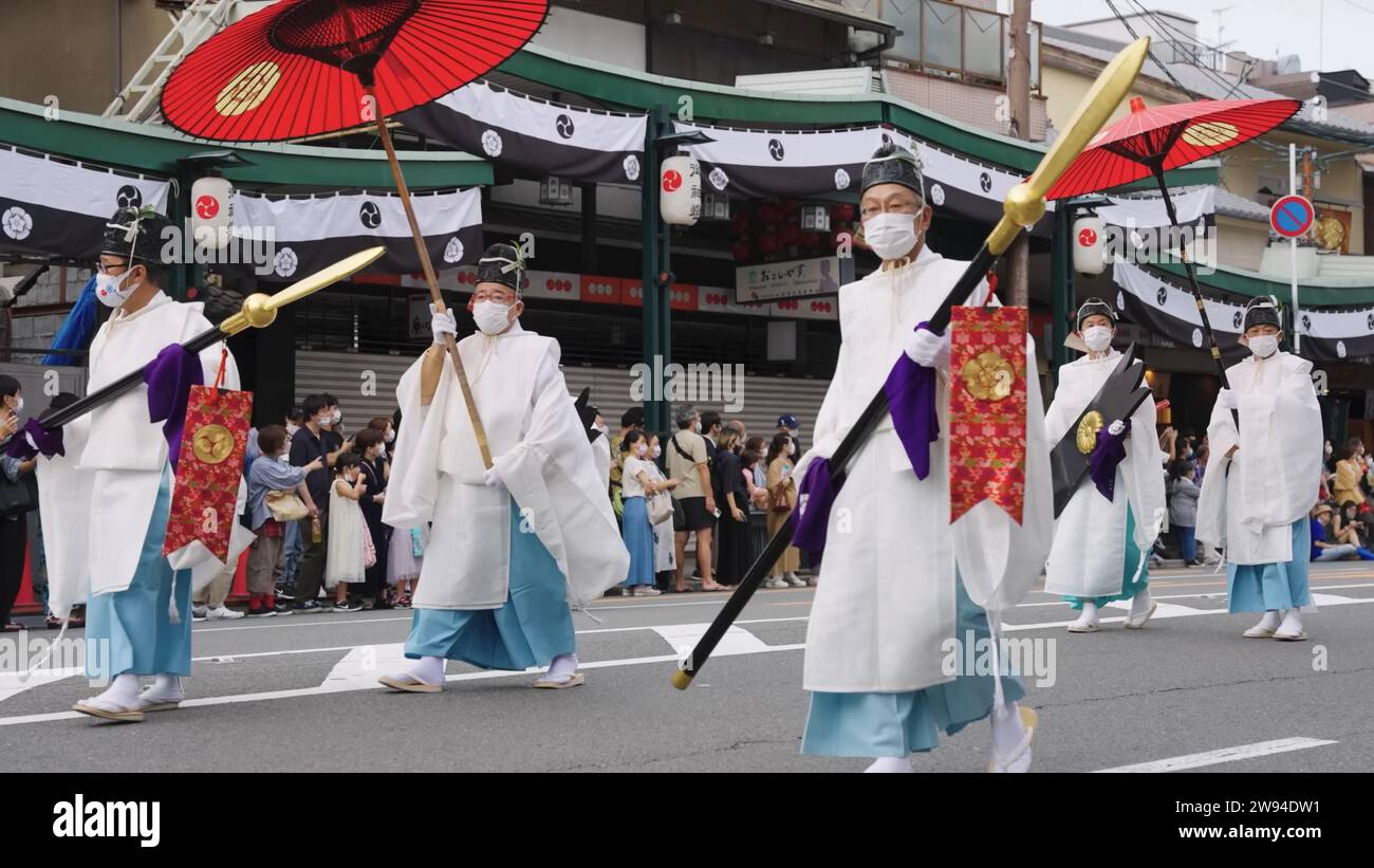 Aperçu du festival Aoi Matsuri à Kyoto au Japon présentant un homme orné d'une tenue traditionnelle tenant gracieusement un parapluie rouge vibrant Banque D'Images