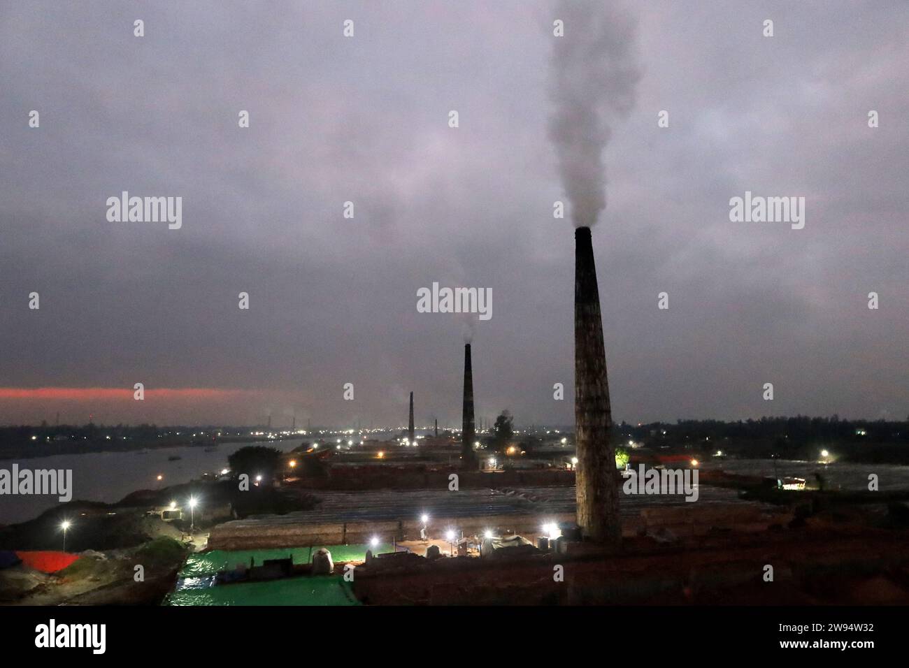 Sirajdikhan, Munshiganj, Bangladesh. 24 décembre 2023. La fumée émane d'un four à briques sur la rive de la rivière Dhaleshwari dans Sirajdikhan upazila de Munshiganj. Ces fumées émises pour brûler les briques contiennent diverses substances nocives, y compris le dioxyde de carbone et le monoxyde de carbone, qui sont nocifs pour l'environnement, les cultures et les personnes. Par conséquent, le gouvernement a interdit la construction de fours à briques dans la ville. (Image de crédit : © Syed Mahabubul Kader/ZUMA Press Wire) USAGE ÉDITORIAL SEULEMENT! Non destiné à UN USAGE commercial ! Crédit : ZUMA Press, Inc./Alamy Live News Banque D'Images