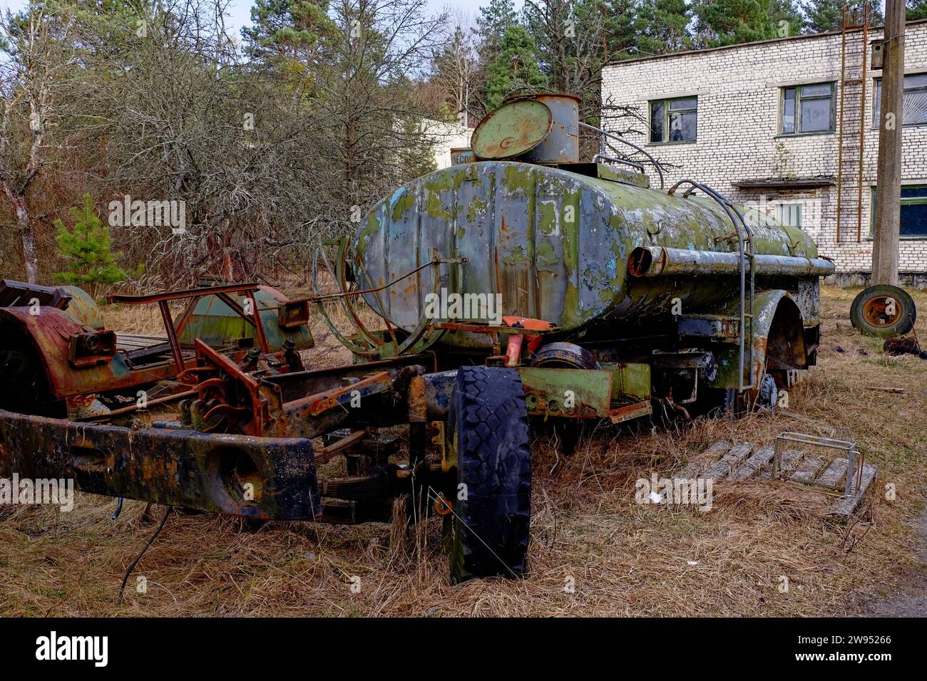 Un vieux camion-citerne rouillé abandonné dans une zone boisée. Banque D'Images