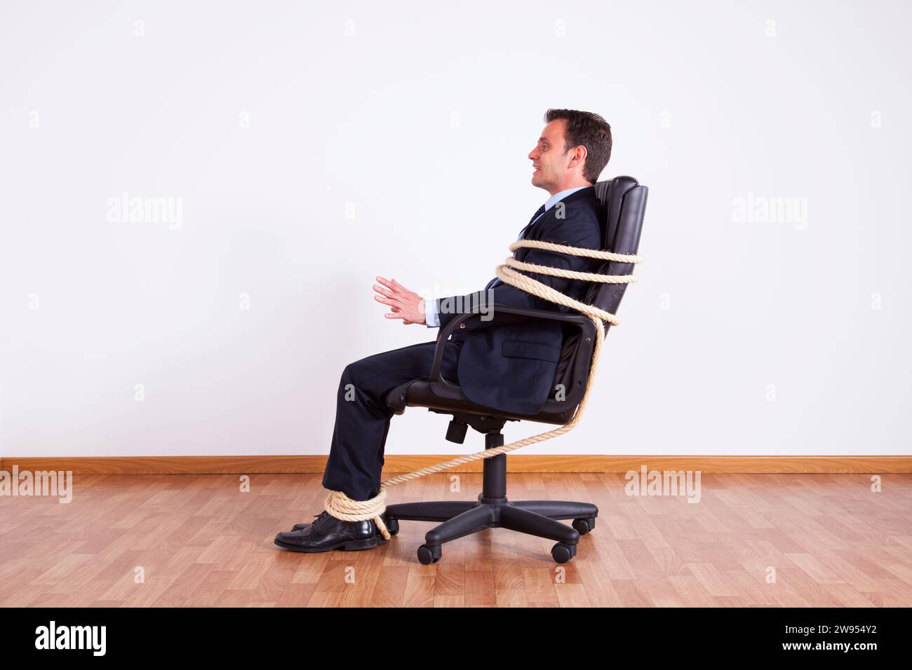 Businessman tied up avec une corde lutte pour obtenir gratuitement Banque D'Images