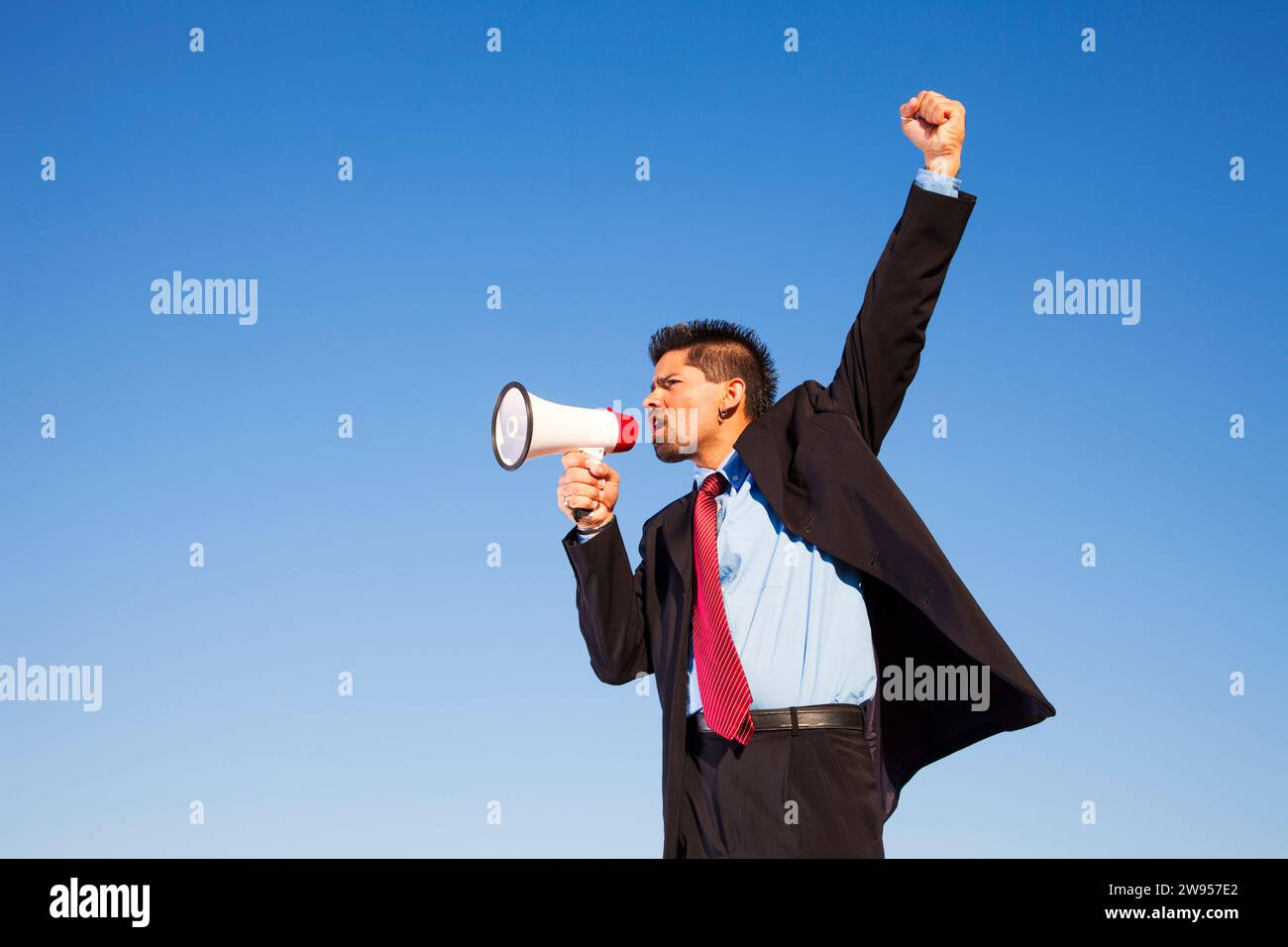 Businessman speaking avec un mégaphone avec le bleu du ciel comme arrière-plan (photo grand format) Banque D'Images