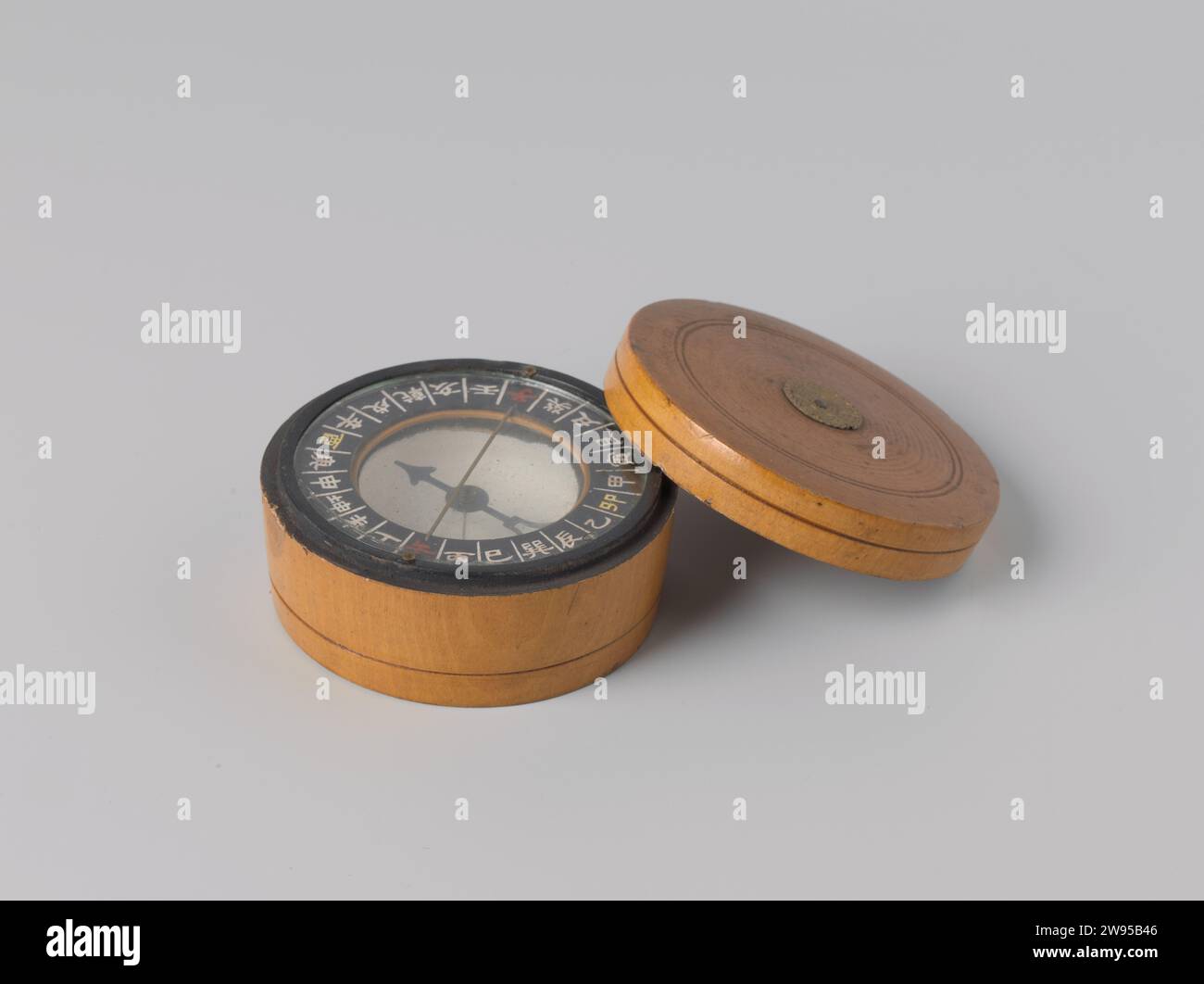 Boussole chinoise, PAE Sze Co., 1850 - 1899 boussole boussole chinoise composée d'un bol, peint en blanc à l'intérieur et recouvert de verre, contenant une aiguille de boussole sèche. Les boussoles chinoises ont une subdivision en 24 directions de vent. Les directions du vent sont indiquées en caractères blancs, le nord et le sud sont indiqués en rouge, l'est et l'ouest en Geel. Noord-Zuid est également représenté par un fil métallique. Bois de Yantai (matière végétale). verre. métal. cuivre (métal) Banque D'Images