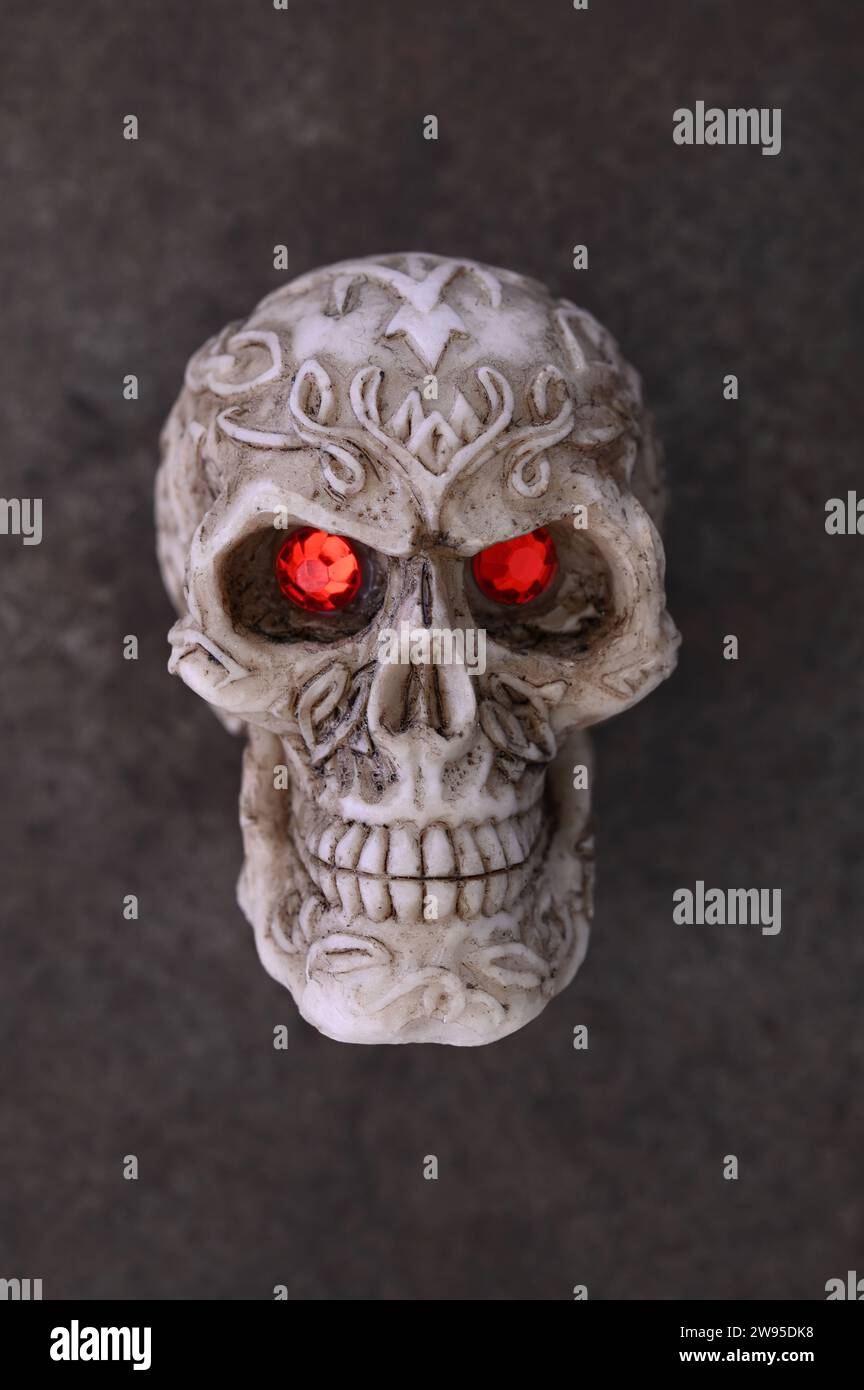 Modèle de crâne humain avec un motif complexe et des yeux de bijoux rouges regardant Banque D'Images