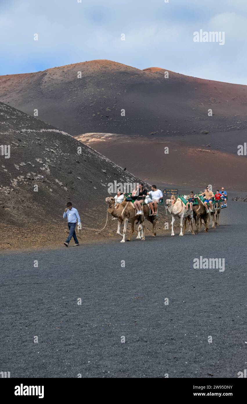 Touristes faisant des promenades à dos de chameau dans le parc national de Timanfaya, îles Canaries, également connu sous le nom de Parque Nacional de Timanfaya Banque D'Images