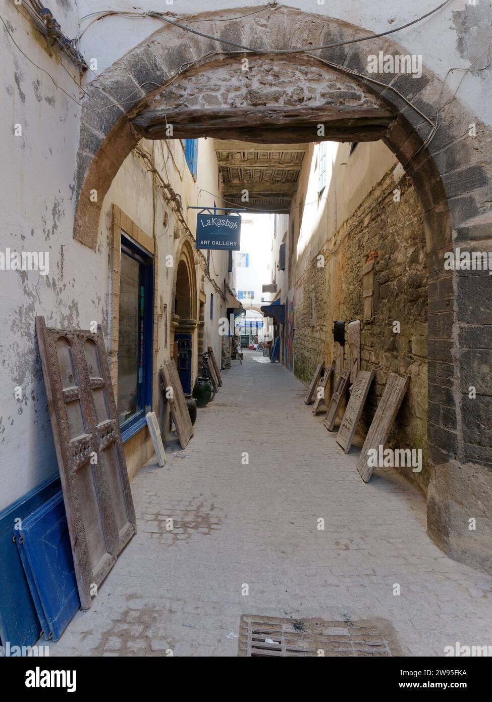 Rue étroite dans la médina historique avec des arches et des cadres de porte appuyés contre les murs à Essaouira, Maroc. 23 décembre 2023 Banque D'Images