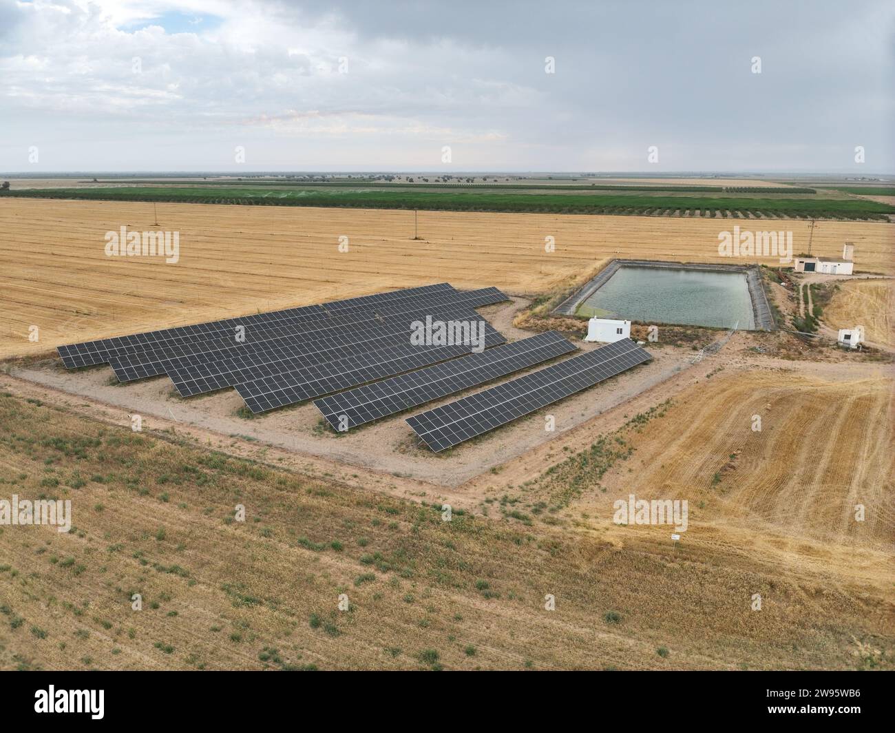 Vue aérienne de l'usine de panneaux solaires pour créer de l'énergie électrique propre industrielle à côté d'un étang d'irrigation agricole. Tir par drone Banque D'Images