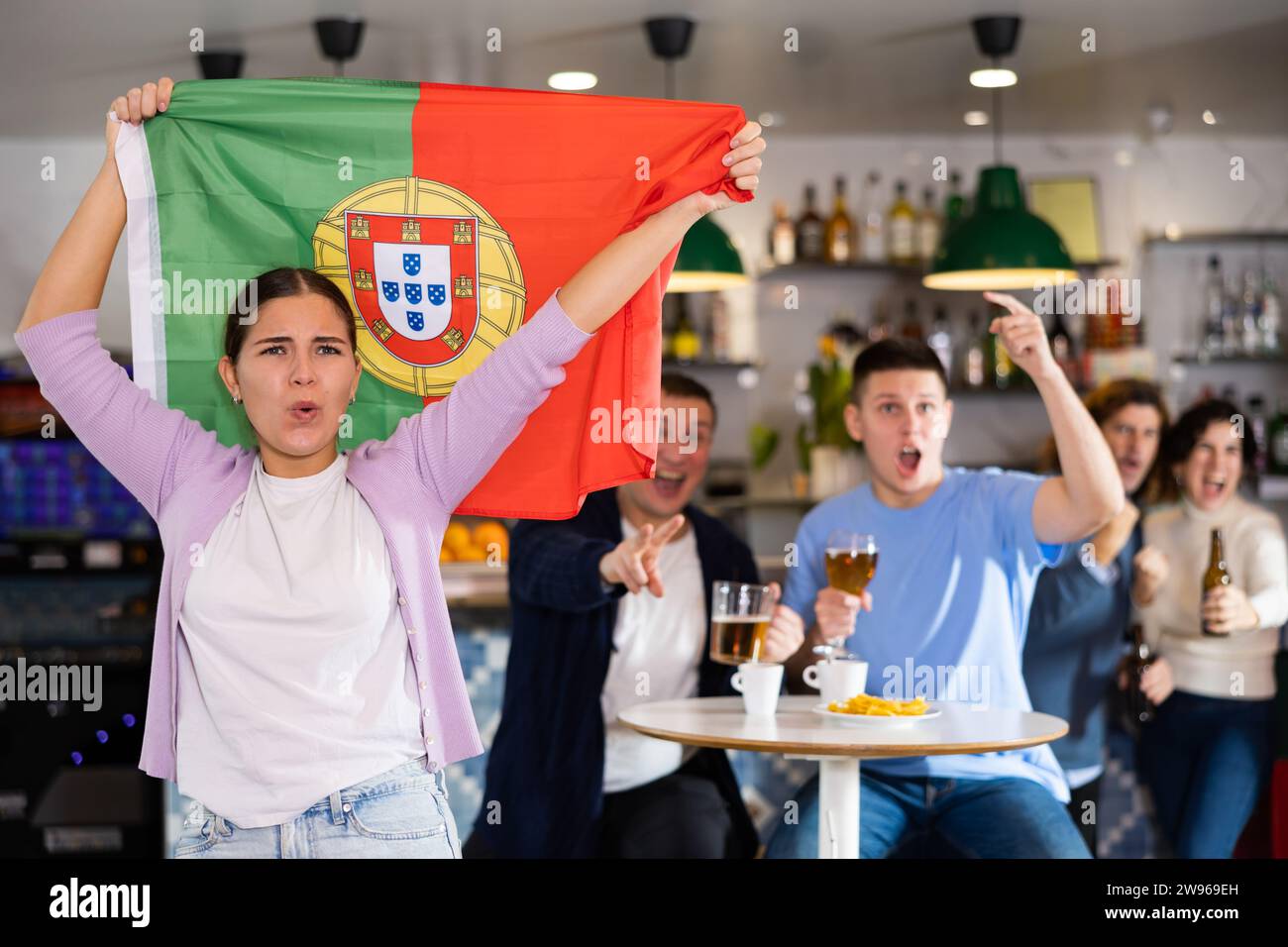 Les fans du drapeau du Portugal célèbrent la victoire de leur équipe préférée au bar à bière Banque D'Images