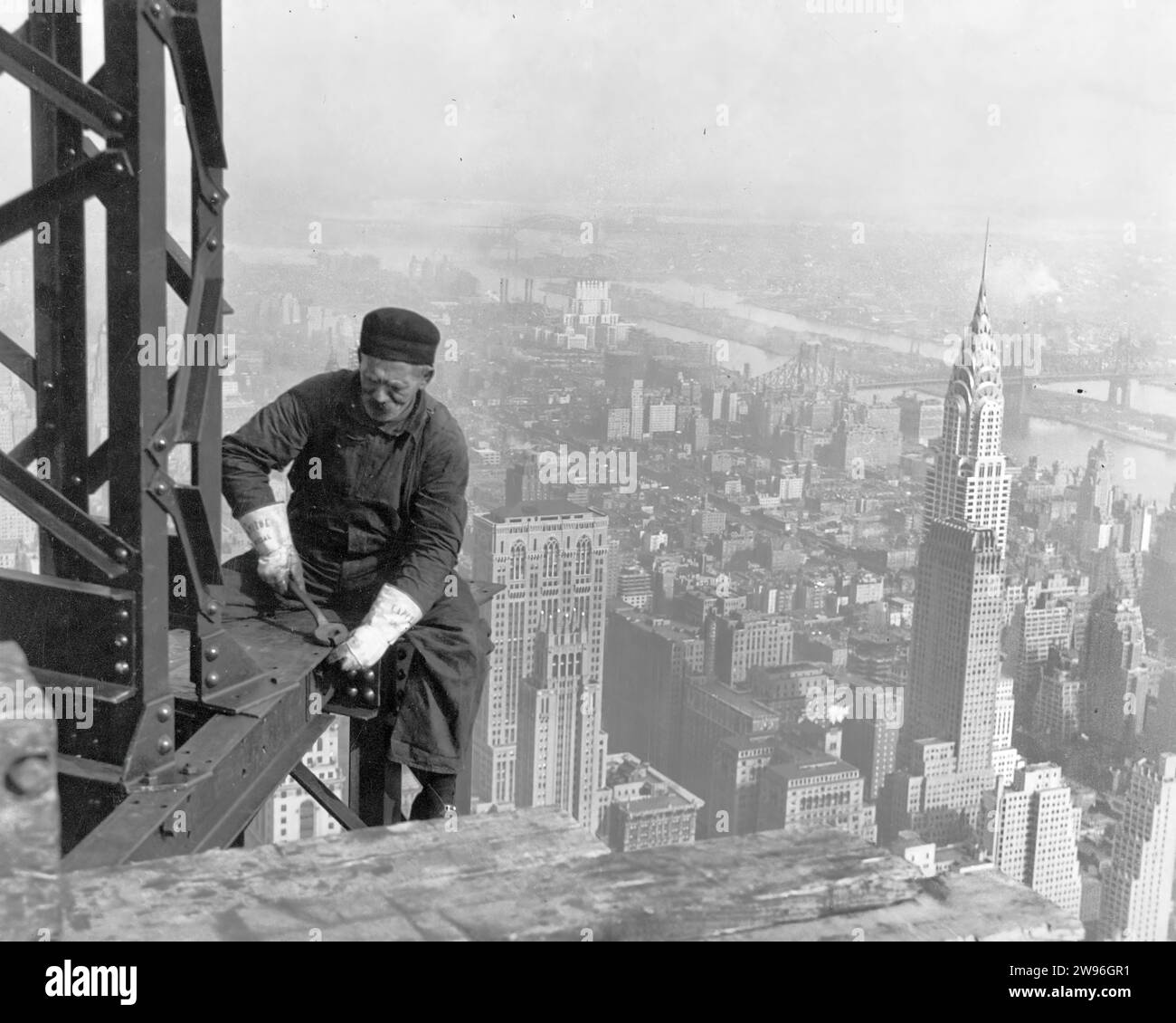 New York, États-Unis - 1930 : un homme blanc blanc célibataire d'âge moyen travaillant seul sur une poutre en acier dans un immeuble de grande hauteur à New York Banque D'Images