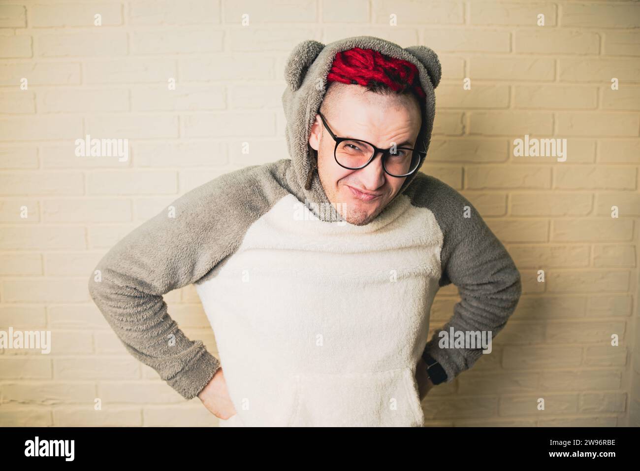 jeune homme hipster attrayant avec des dreadlocks rouges dans des lunettes et un pull blanc sur le fond d'un mur de briques. Banque D'Images