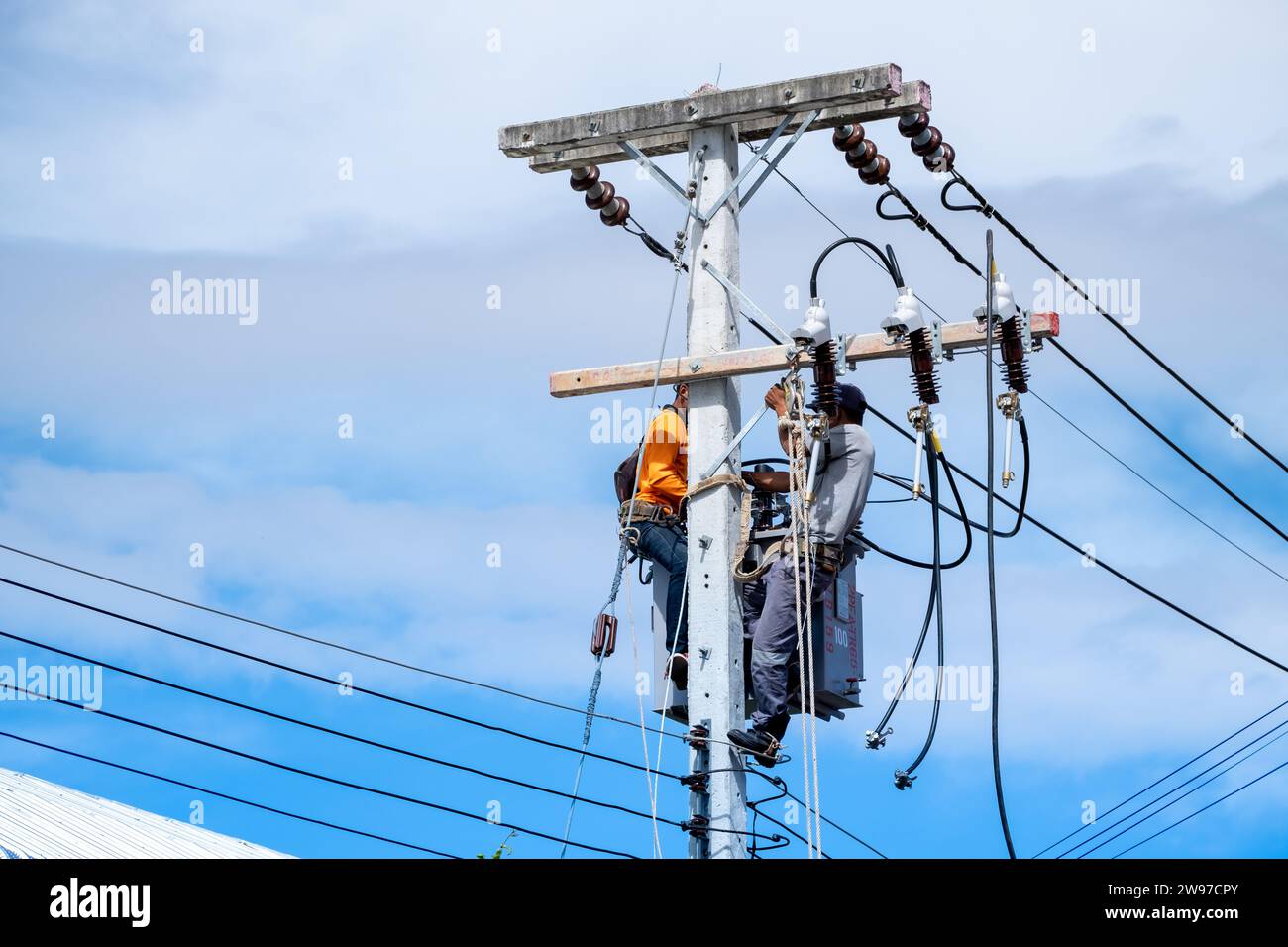 Les ouvriers de réparation de lineman électricien grimpent sur le poteau électrique pour installer ou réparer la ligne électrique. Banque D'Images