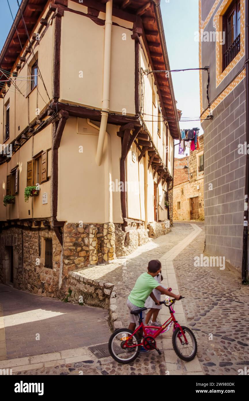 Enfants jouant avec un vélo rouge à Poza del Sal (Castille-et-León, Espagne) Banque D'Images