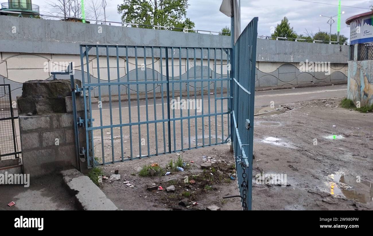 Une porte en métal bleu se dresse devant une clôture de piquet blanche et un bâtiment en briques, créant un look rustique classique Banque D'Images