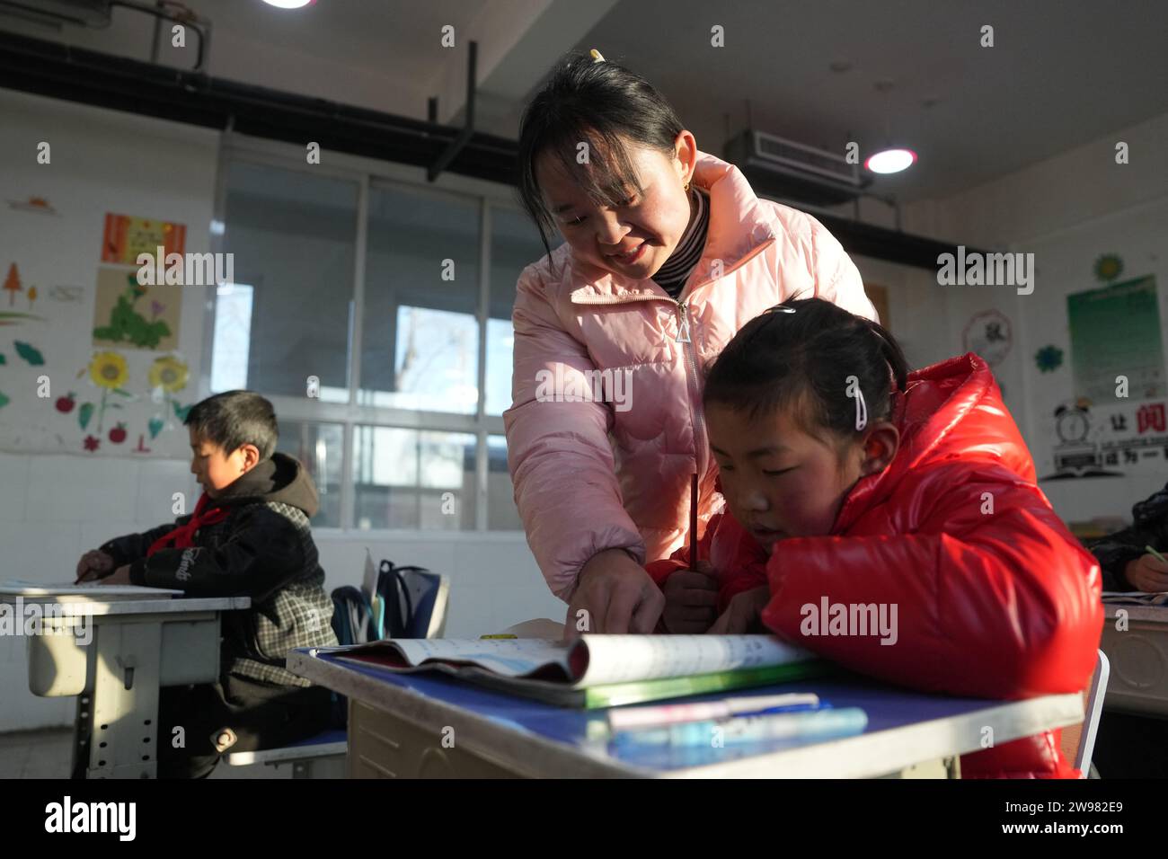 Jishan, province chinoise du Gansu. 25 décembre 2023. Un enseignant instruit un élève d'une école primaire du canton de Liugou, dans le comté de Jishan, dans la province du Gansu, au nord-ouest de la Chine, le 25 décembre 2023. Les écoles primaires et secondaires dans les zones de Jishishan touchées par le séisme ont commencé à reprendre les cours lundi après un contrôle de sécurité. Crédit : Chen Bin/Xinhua/Alamy Live News Banque D'Images