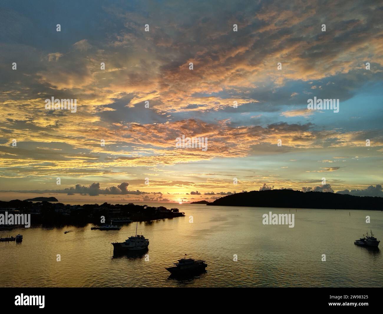 Une scène de lac tranquille avec plusieurs bateaux à voile avec des nuages colorés se reflétant dans la surface de l'eau comme un miroir Banque D'Images