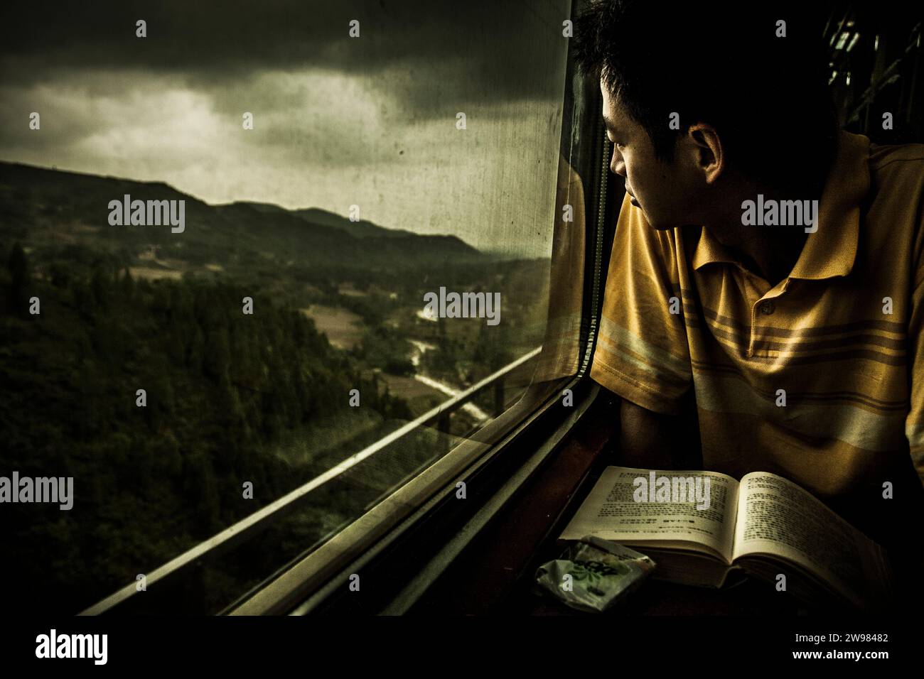 Un jeune Chinois regardant par une fenêtre de train. Banque D'Images
