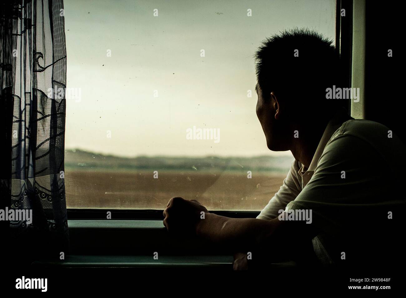 Un Chinois regardant le monde passer par une fenêtre de train. Banque D'Images