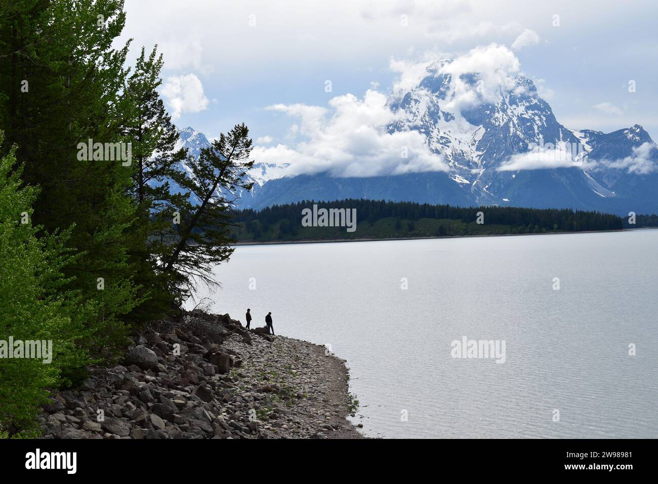Silhouette de deux personnes debout sur la rive du lac Jackson avec les sommets majestueux de la chaîne de montagnes Grand Teton en arrière-plan Banque D'Images