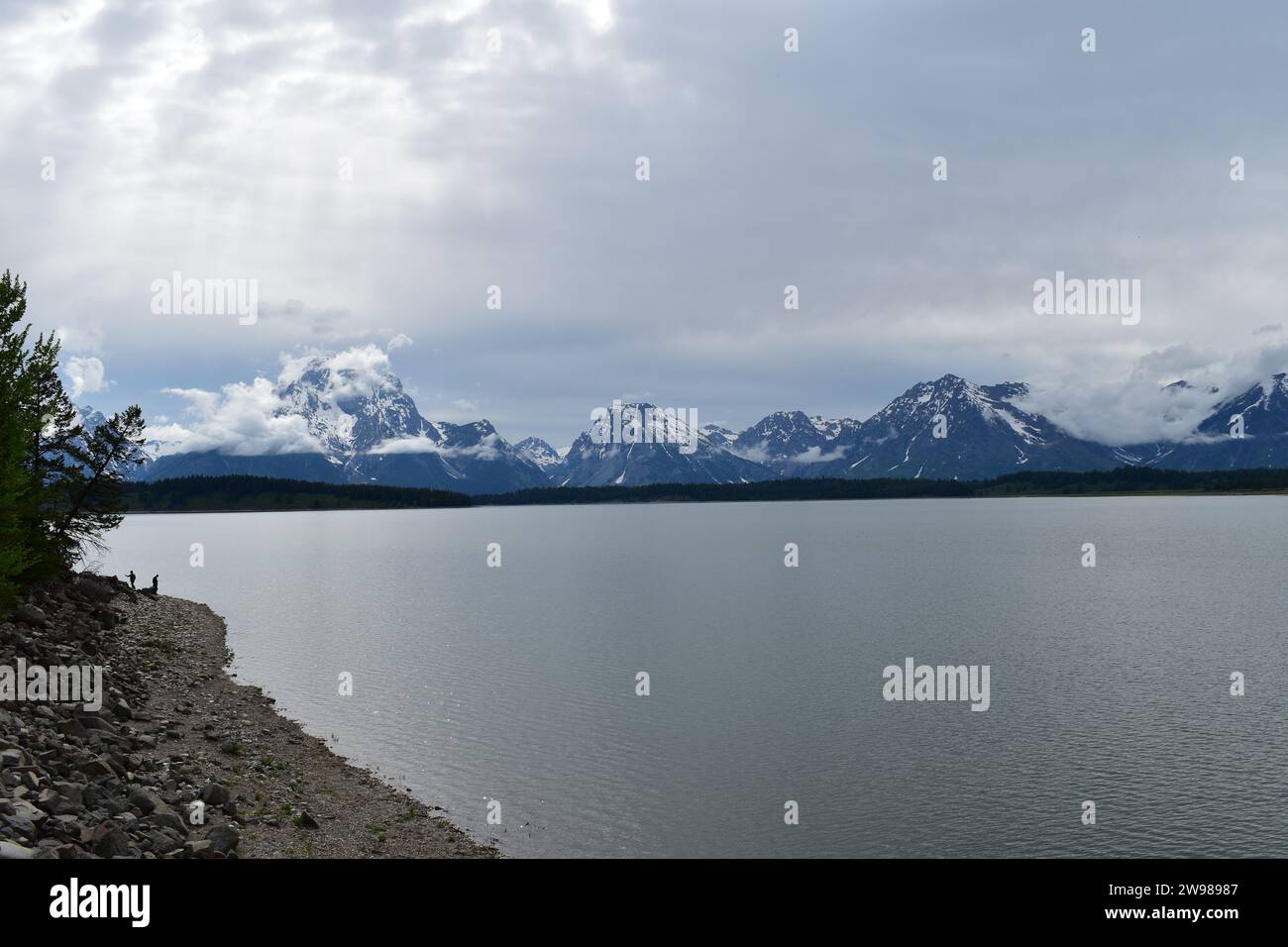 Silhouette de deux personnes debout sur la rive du lac Jackson avec les sommets majestueux de la chaîne de montagnes Grand Teton en arrière-plan Banque D'Images