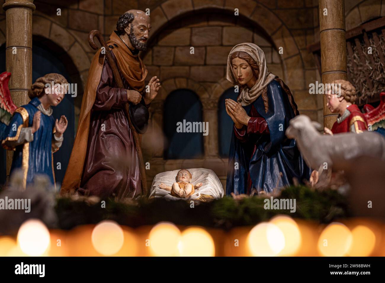 25 décembre 2023, Basse-Saxe, Osnabrück : une scène de nativité peut être vue dans la cathédrale derrière des bougies allumées. Beaucoup de services religieux sont bien fréquentés pendant les vacances de Noël. Photo : Moritz Frankenberg/dpa Banque D'Images