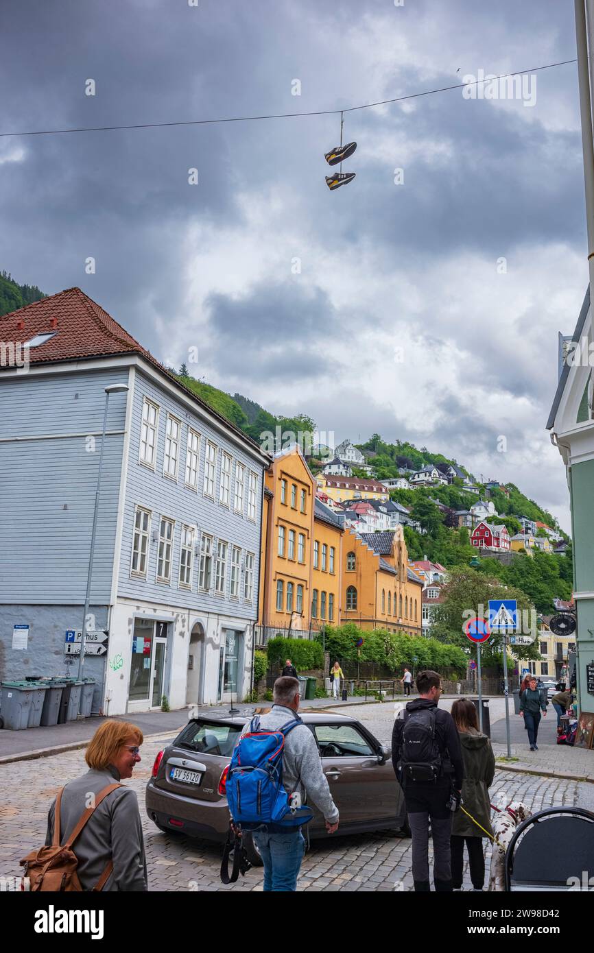 Bergen, Norvège, le 22 juin 2023 : un groupe de personnes marche sur une rue pavée vacante dans le centre-ville de Bergen après une tempête de pluie. Les chaussures pendent Banque D'Images