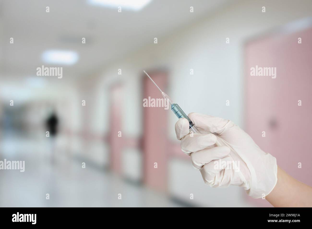 main avec gant de protection injectant du médicament avec fond de couloir intérieur de l'hôpital Banque D'Images