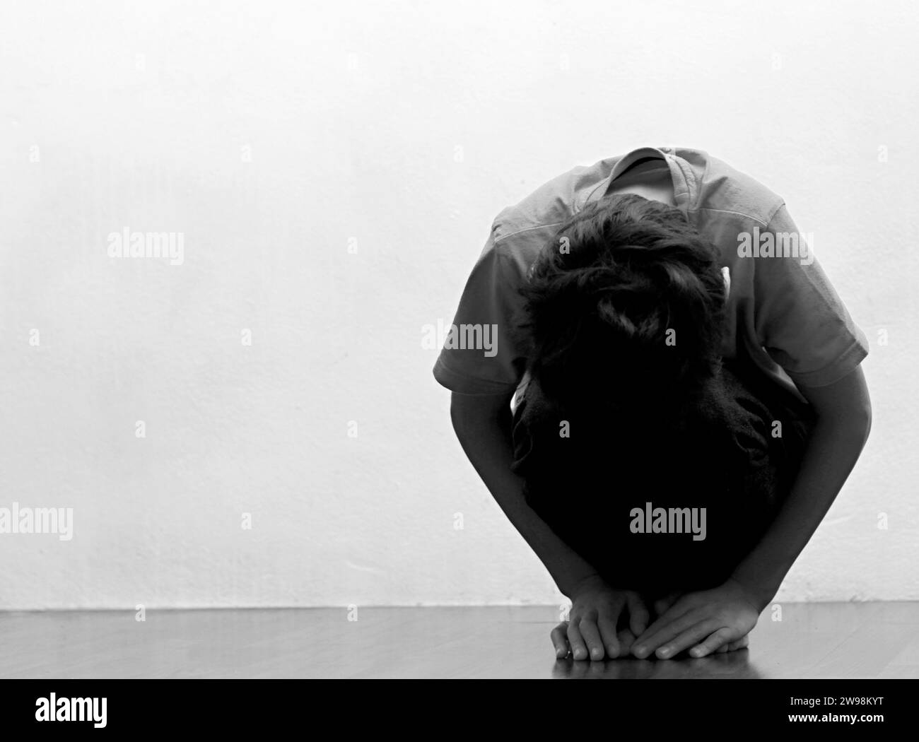 garçon priant dans la pauvreté sur le plancher image stock sans aide pleurant seul et tout seul sur fond blanc photo stock Banque D'Images