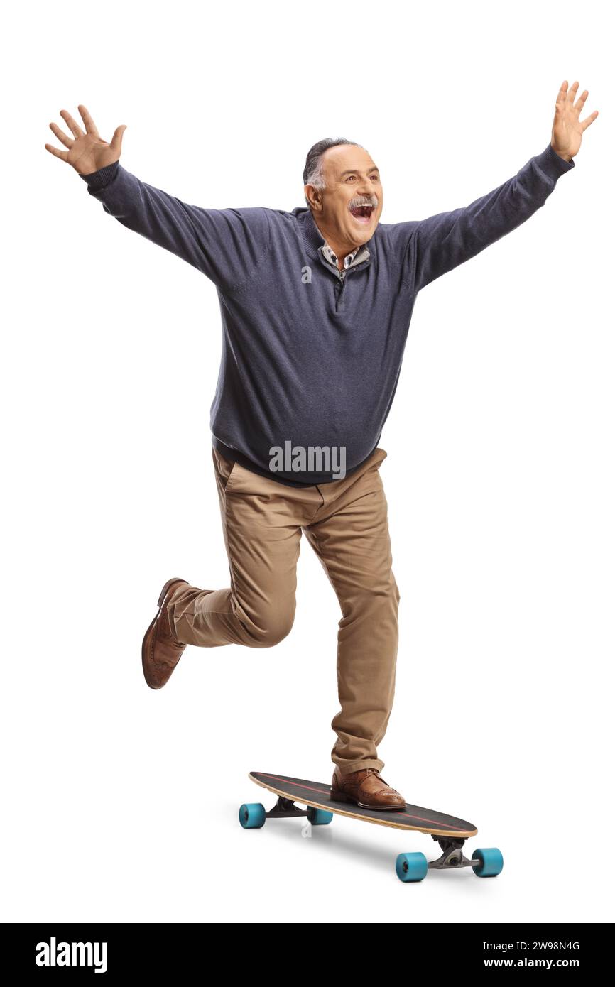 Homme mature excité chevauchant un skateboard et écartant les bras isolés sur fond blanc Banque D'Images