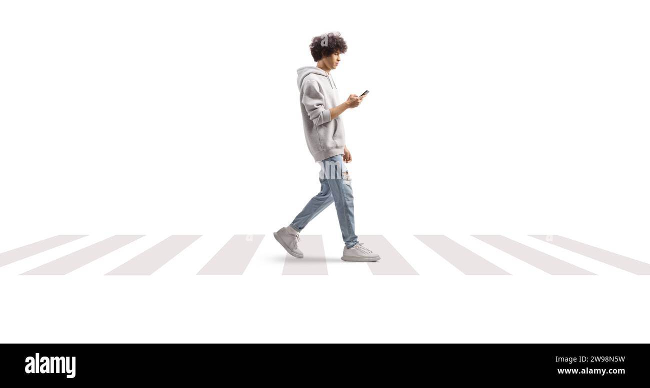 Jeune homme portant un sweat à capuche gris et traversant une rue avec un smartphone isolé sur fond blanc Banque D'Images