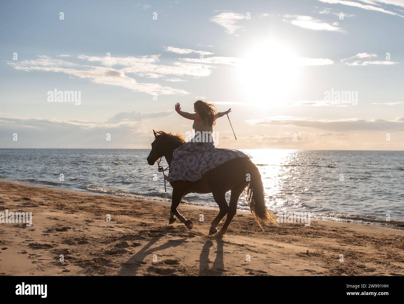 Une jeune femme adulte joyeusement montée à cheval sur une plage par une journée ensoleillée Banque D'Images
