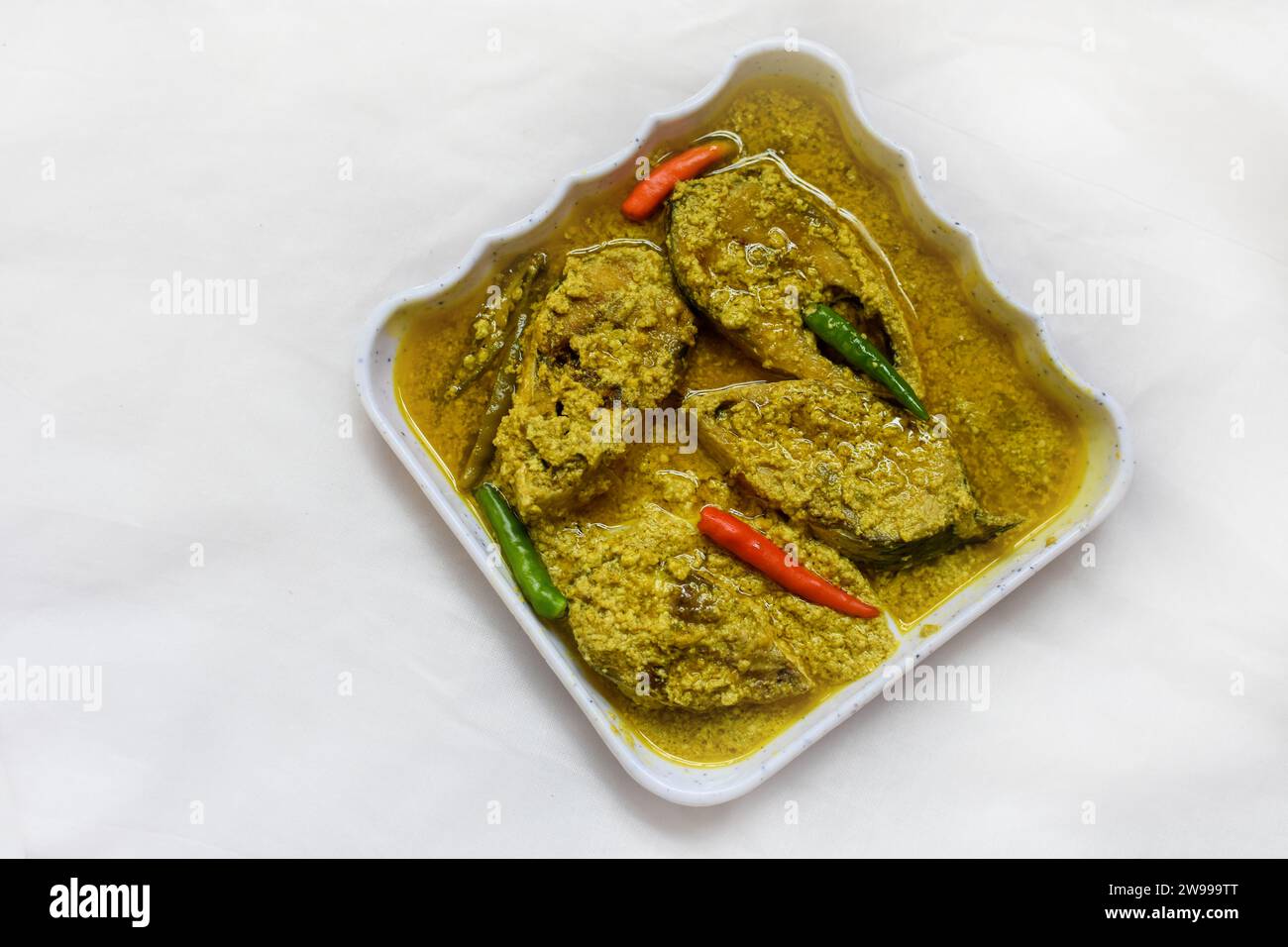 Une assiette blanche avec un délicieux assortiment de poissons hilsa recouverts de piment vert aromatique Banque D'Images