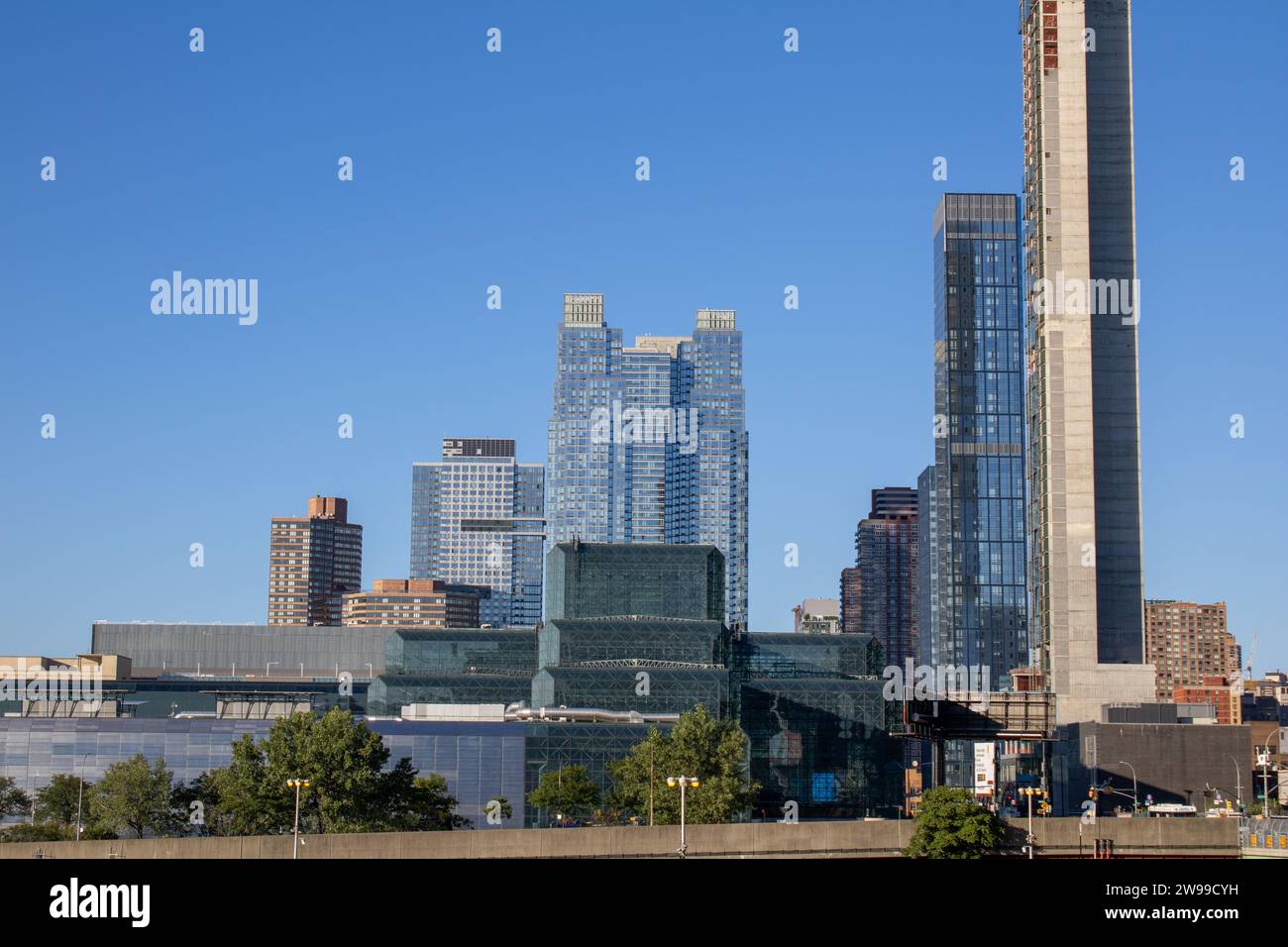 Une imposante tour de l'horloge est située derrière un grand bâtiment dans une ville animée, offrant une perspective unique du paysage urbain Banque D'Images