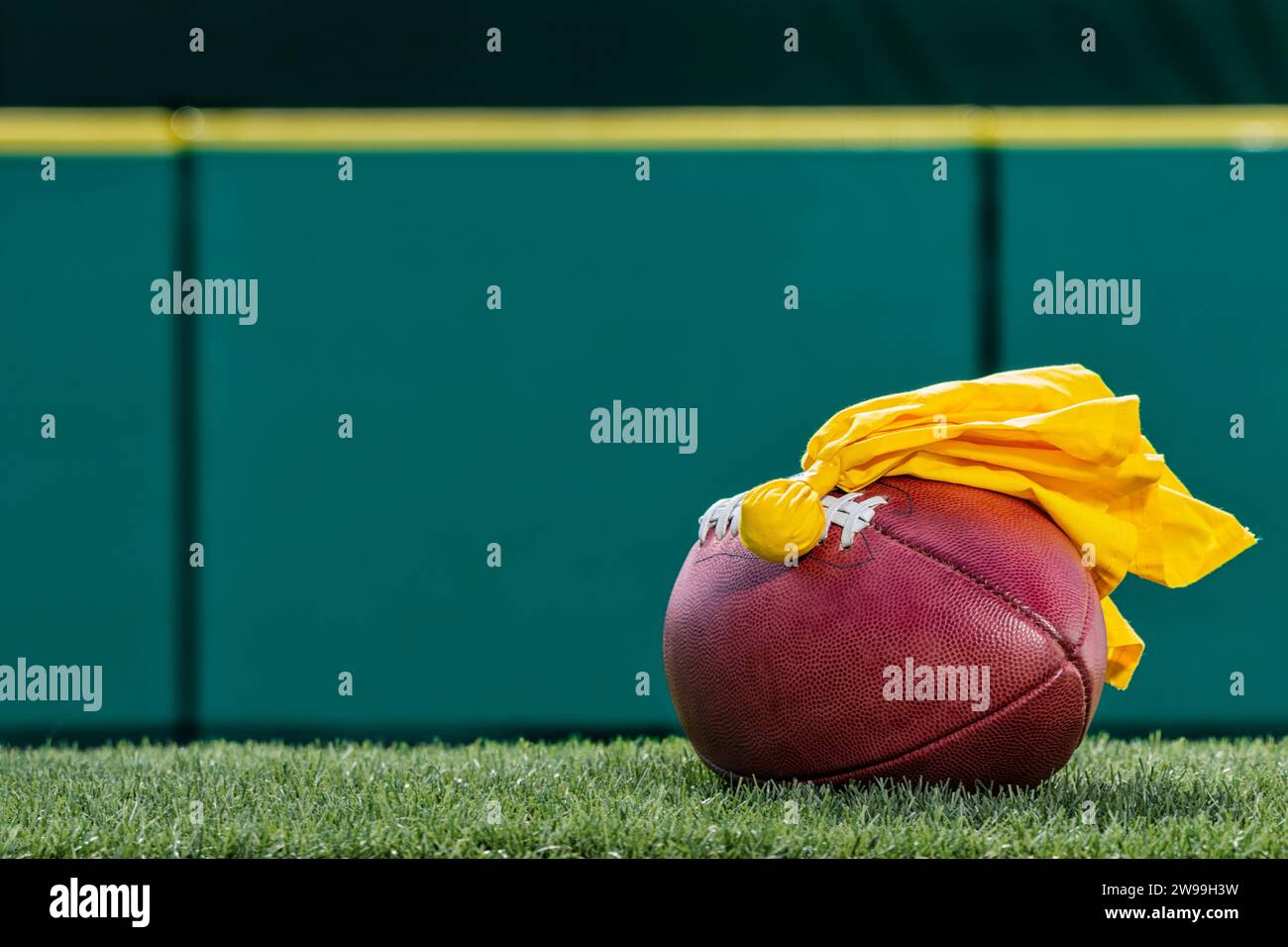 Un ballon de football américain avec un drapeau de pénalité jaune assis sur le dessus Banque D'Images