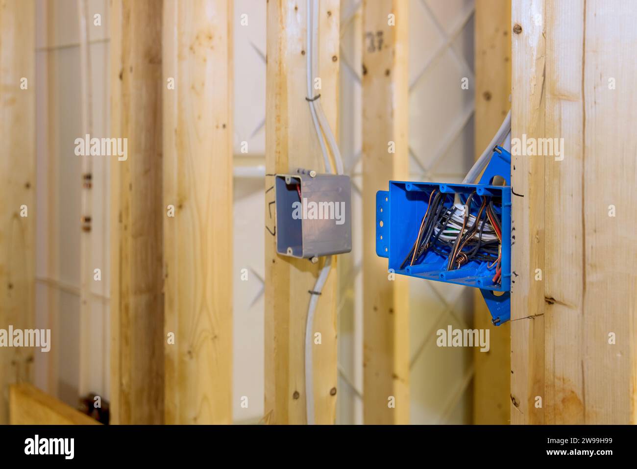 Situé sur le mur au-dessus de la poutre de cadre en bois est un boîtier de commutation électrique en plastique avec des fils Banque D'Images
