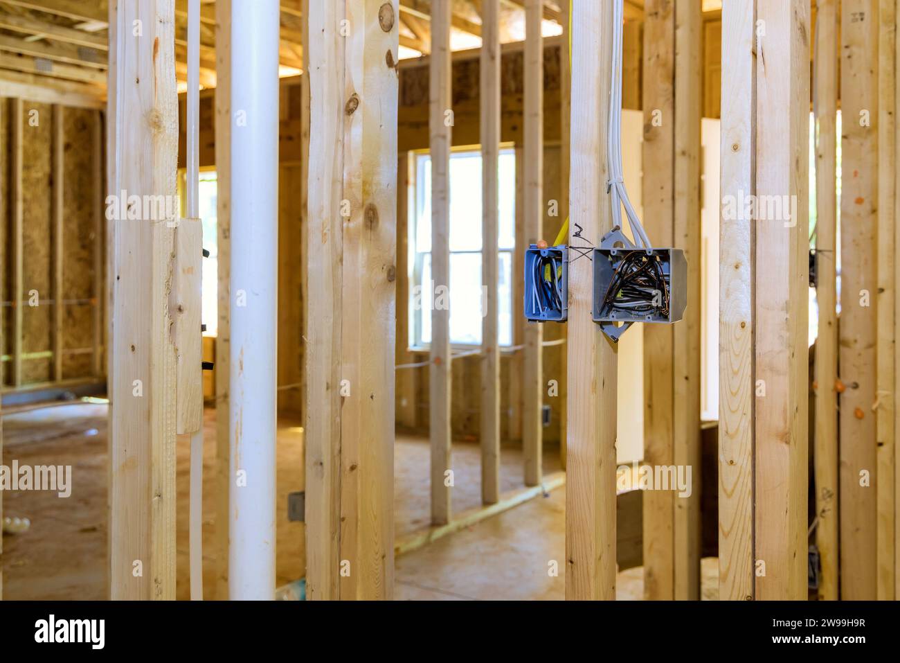 Le boîtier de commutation électrique en plastique est monté sur des poutres de cadre en bois sur le mur avec des fils qui le traversent Banque D'Images
