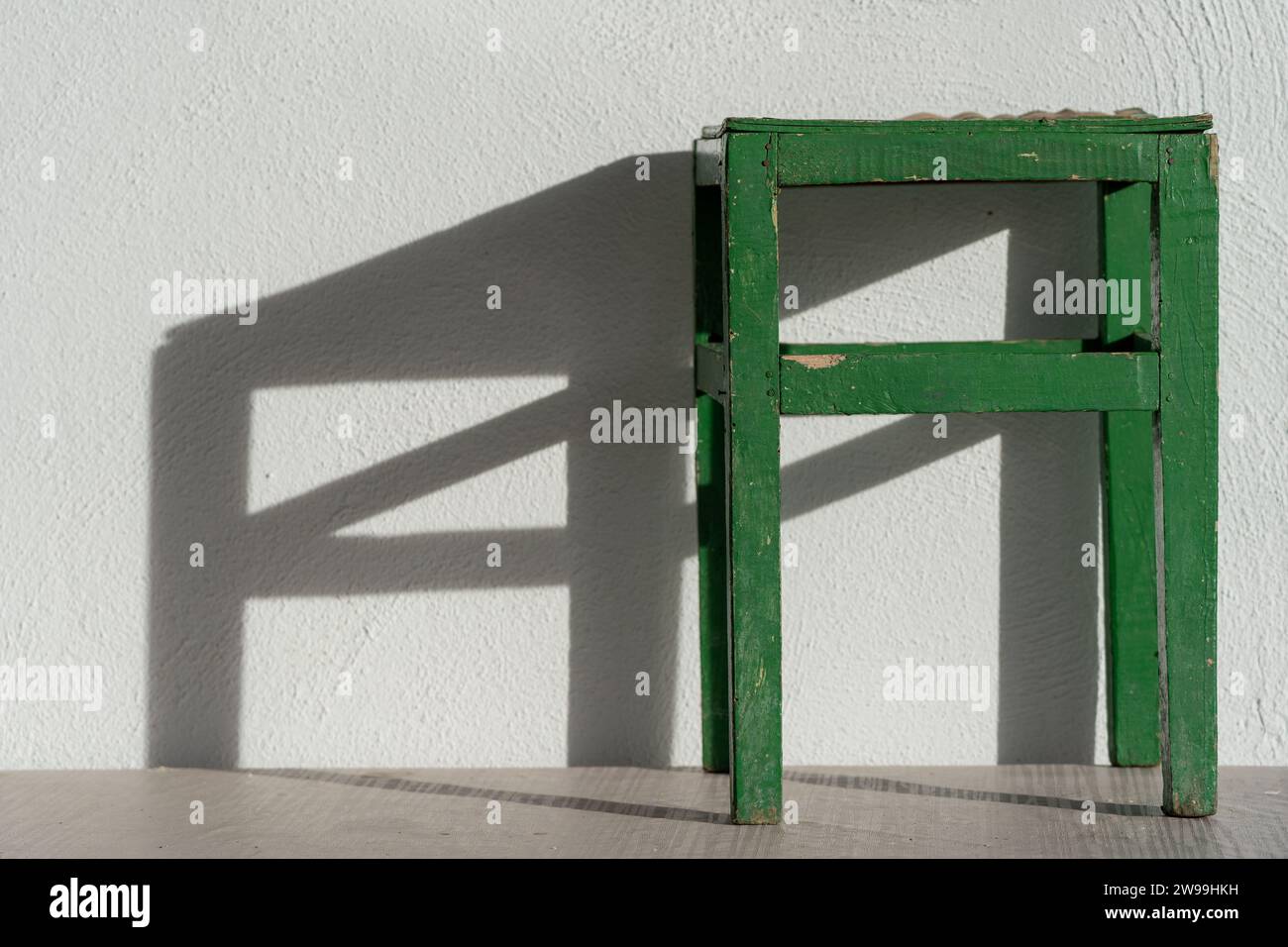 Éclairage vert de chaise sur le fond de mur blanc. Lumière et ombre. Banque D'Images
