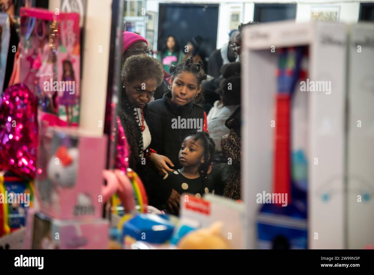 New York, États-Unis. 25 décembre 2023. Les enfants attendent pour choisir des jouets pendant le dîner de Noël et la distribution de jouets du National action Network (NAN) à la Maison de Justice à Harlem, New York, États-Unis, le 25 décembre 2023. NAN a offert des repas et des jouets gratuits aux résidents locaux à la Maison de Justice à Harlem lundi. Crédit : Michael Nagle/Xinhua/Alamy Live News Banque D'Images
